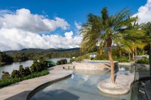 瓜塔佩Tau House的游泳池,旁边是一条河流,旁边是棕榈树