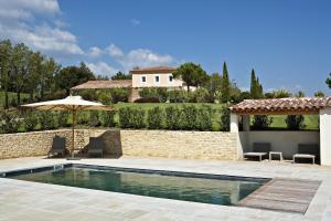 加尔加斯Coquillade Provence的一个带遮阳伞和房子的游泳池