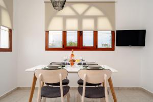 米科利维亚Orkos Naxian Wave 3的一间配备有白色桌椅的用餐室
