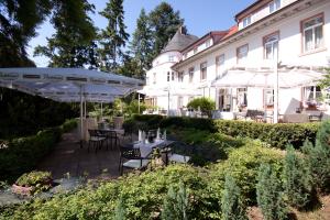 达姆施塔特霍夫古特迪普斯霍夫酒店及KG餐厅的一座花园,在一座建筑前设有桌子和遮阳伞