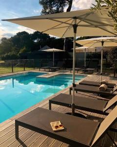 卡纳克Villa Mané Lann Maison d'hôtes & spa的一个带2把躺椅和遮阳伞的游泳池
