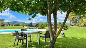 比利亚卡约casa rural de un artista en plena naturaleza piscina y parque de esculturas en villarcayo的游泳池旁树下的桌椅