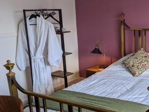 OlneyCowpers Oak的一间卧室配有一张挂在架子上的长袍的床