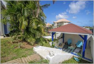 圣吕斯Villa Mango 150 mètres plage à pied的一座带凉亭和两把椅子的房子,还有一棵棕榈树