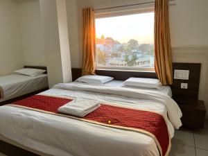 巴德拉恰拉姆SRI BHAVYARESIDENCY的带窗户的客房内的三张床
