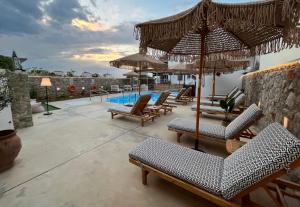 斯卡拉Koukounari Apartments的一个带椅子和遮阳伞的庭院和一个游泳池