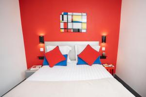 巴黎杜蒙特多尔巴蒂尼奥勒酒店的红色卧室配有白色的床和红色和蓝色枕头