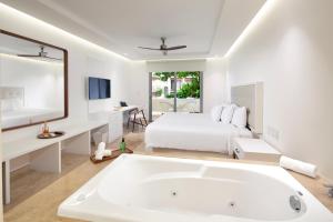 普拉亚卡门Antera Hotel & Residences的白色卧室设有大浴缸和一张床