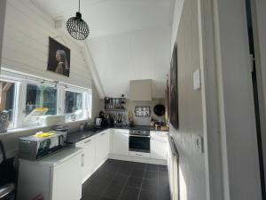 WijdenesVakantiehuis Het Uilennest的厨房配有白色橱柜和黑色瓷砖地板。