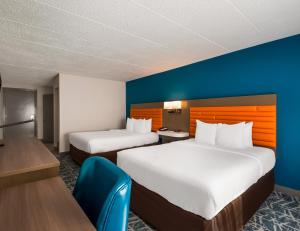 福尔斯彻奇Comfort Inn Falls Church - Tysons Corner的酒店客房设有两张床和蓝色的墙壁。