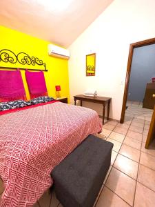 卡波圣卢卡斯Sofia Hostel Cabo的一间卧室配有一张粉红色和黄色墙壁的床