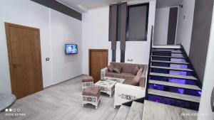 古莱比耶Kelibia beach luxury maison的一间带楼梯和沙发的客厅