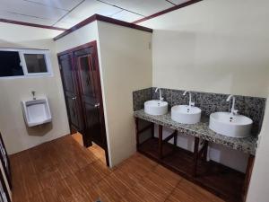 乌蒂拉Fenix Hotel & Hostel的浴室设有2个盥洗盆、小便器和2面镜子