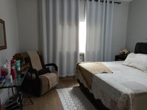 瓜拉廷格塔Casa da Nice的卧室配有床、椅子和窗户。