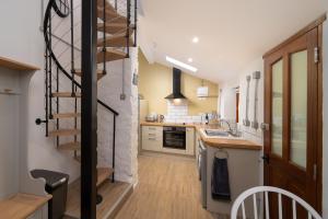 林顿Coachman's Quarters的厨房设有螺旋楼梯,毗邻带水槽的厨房