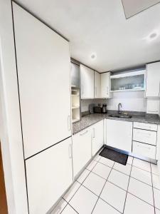 伦敦New Beautiful Lux Apartment的白色的厨房配有白色橱柜和瓷砖地板。