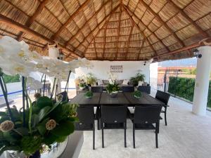 巴亚尔塔港Hotel Suites Mar Elena的木屋顶下的餐桌和椅子