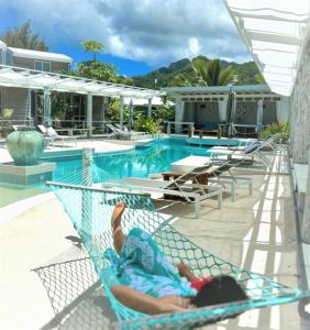 拉罗汤加Ocean Escape Resort & Spa的躺在游泳池旁的吊床上的人