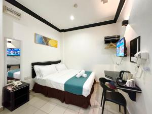 哥打京那巴鲁Hotel Tourist City Centre by HotSpot Essential的酒店客房设有一张床、一张书桌和一台电视机。