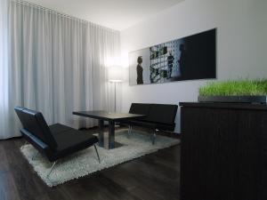 林茨arte Hotel Linz的客厅配有桌椅和电视。