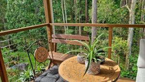 DoonanDeluxe Studio with Forest Views, Noosa Hinterland的阳台配有桌子、长凳和桌椅。