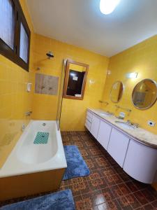 蒙特韦尔迪Chalés Monte Verde的黄色的浴室设有浴缸和两个水槽