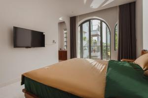 岘港Gom House的一间卧室设有一张大床和一台平面电视。