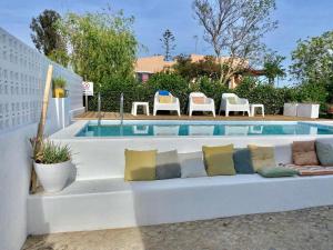 法鲁Casa Pedra Rosa - VINHAS de NEXE的游泳池畔的白色沙发,配有枕头