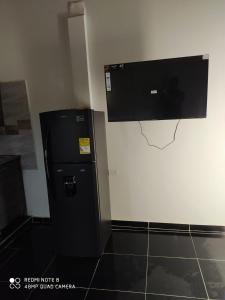 巴亚索拉诺Apartamentos Olaya!的壁挂式平面电视的黑色冰箱