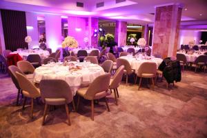 什蒂普Oaza Hotel的宴会厅配有桌椅和紫色照明