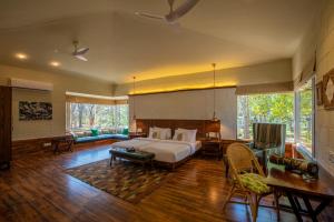 坎哈The Riverwood Forest Retreat - Kanha的卧室配有一张床和一张桌子及椅子