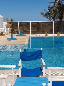 Al ḨaddādahDar Lagune Djerba的游泳池旁的蓝色椅子
