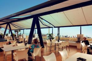 奇皮奥纳Hotel Vértice Chipiona Mar的餐厅设有白色的桌子和白色的椅子及窗户。