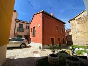 拉·格兰哈·圣·伊尔德Apartamentos "Casa Abuelo Juan"的停在红色建筑前面的汽车