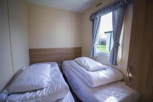 亨斯坦顿Lovely Caravan With Decking At Manor Park Nearby Hunstanton Beach Ref 23017t的一间小卧室,配有两张床和窗户