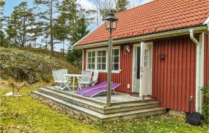 Gräddö2 Bedroom Amazing Home In Grdd的红色小屋,门廊上配有桌椅