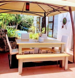 开普敦Regent Casa’s的一张木桌和遮阳伞下的长椅
