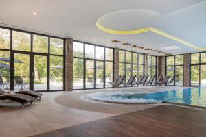 布尔格Landhotel Burg im Spreewald - Resort & Spa的客房设有带椅子和窗户的游泳池。