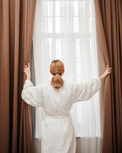 巴库OLF Hotel的穿着白色衣服的女人,从窗户望出去