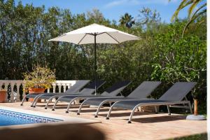 卡武埃鲁Casa Luzerna的游泳池旁一排带遮阳伞的躺椅