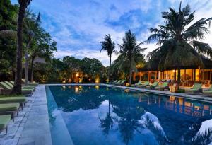 沙努尔Sudamala Resort, Sanur, Bali的一个带躺椅的游泳池,一个度假村