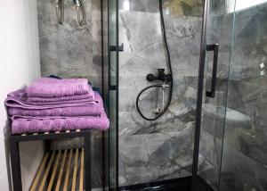 海若克利欧Tiny Villa among the olives的浴室设有淋浴,在长凳上配有紫色毛巾