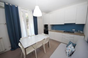 罗索利纳马雷Residence Verdena appartamento 03的厨房配有白色橱柜和白色的桌椅