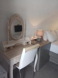 FoinikiáAQUA SERENITY LUXURY SUITES SANTORINI的一间卧室配有一张带镜子的桌子和一张床