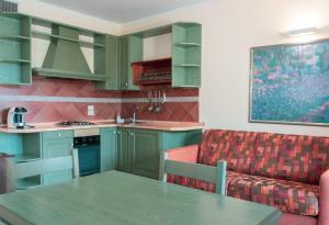 皮亚诺·德勒·皮耶韦阿西西及时行乐生活俱乐部酒店的厨房配有绿色橱柜、桌子和沙发