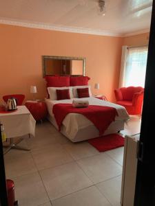 布龙克霍斯茨普雷Sikhula Sonke Guest House的一间卧室配有一张带红色枕头的大床