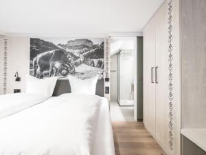 阿彭策尔Traube Restaurant & Hotel的白色卧室的墙上挂着一幅牛的照片