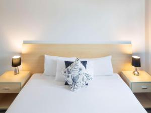 城堡山Mantra Castle Hill Sydney, an Accor Hotel的卧室配有带两盏灯的白色床