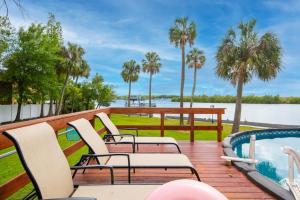 里弗维尤Stunning Tampa Bay Waterfront House with Pool & Boat的一个带椅子的甲板、一个游泳池和棕榈树