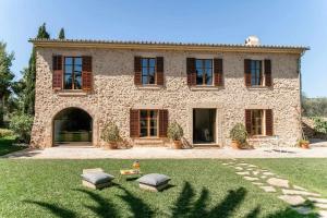 波托尔Premier Villa Rental in Mallorca Es Barranc Vell的一座大石头房子,院子里有两张凳子